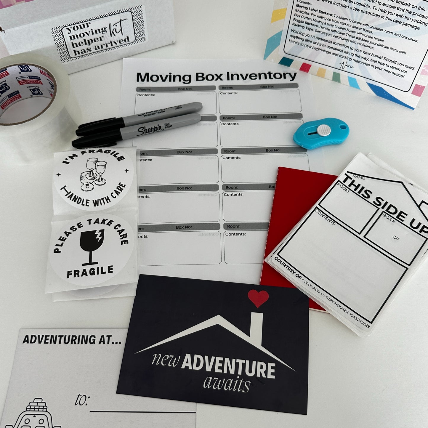 moving helper kit contents sharpie, box cutter, moving box stickers, notebook, just moved postcards, fragile stickers, packing tape, personalized notecard