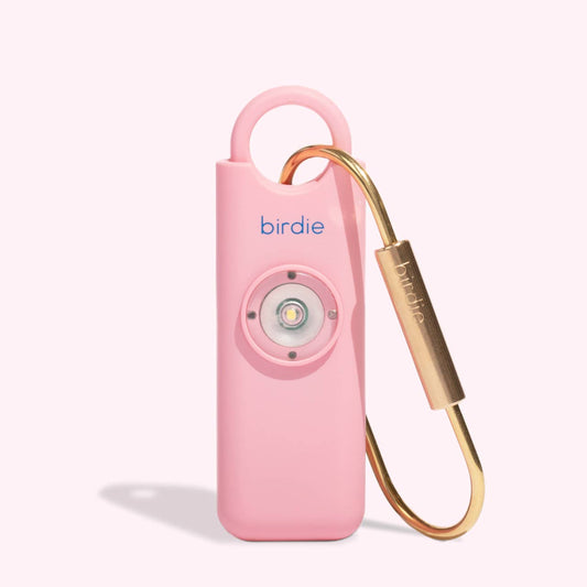 A pink personal safety alarm with a solid brass keychain and a flashing strobe-light feature, branded as 'Birdie'.